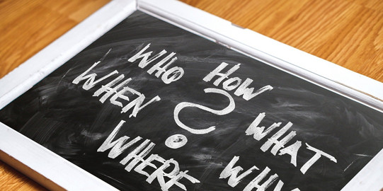 Eine Tafel mit den Fragen "What", "Why", "When", "Who", "Where", "How" 