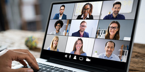 Auf dem Bildschirm eines Laptops sind sechs Menschen zu sehen, die sich in einer Videokonferenz befinden.