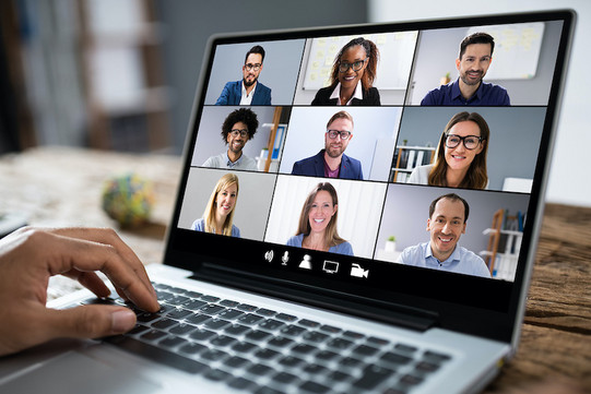 Auf dem Bildschirm eines Laptops sind sechs Menschen zu sehen, die sich in einer Videokonferenz befinden.