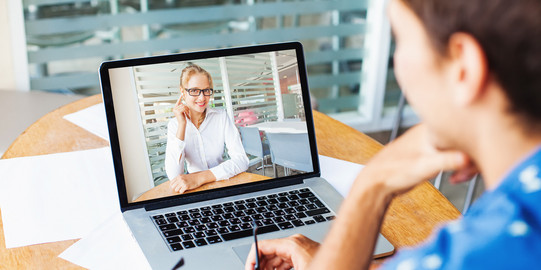 Frau sitzt und hält eine Videokonferenz auf ihrem Laptop mit einer anderen Frau ab