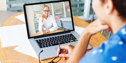 Frau sitzt und hält eine Videokonferenz auf ihrem Laptop mit einer anderen Frau ab